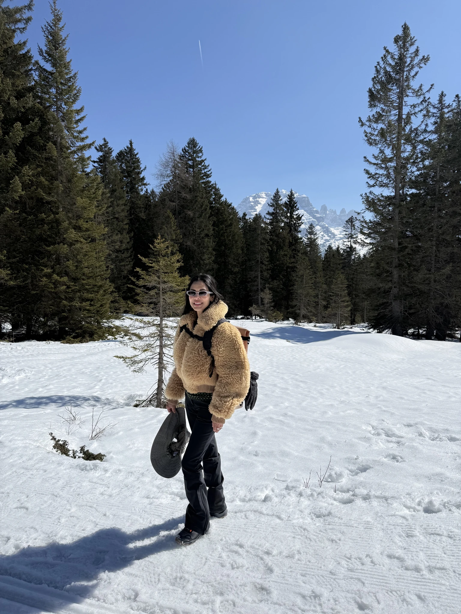 Traveler standing in a snowy forest with the Dolomite mountains in the background